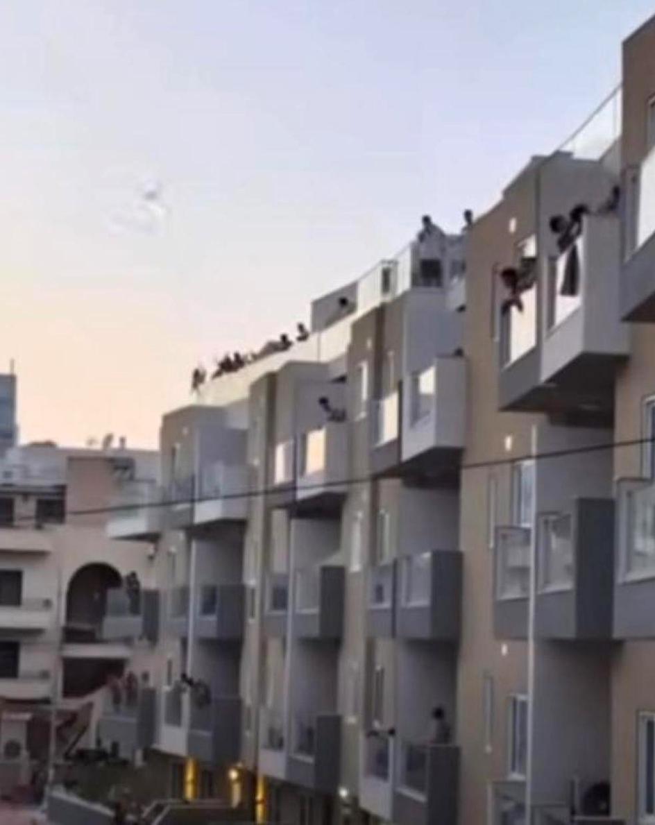 Youths jeering and throwing bottles and cans onto the street below in Swieqi.
