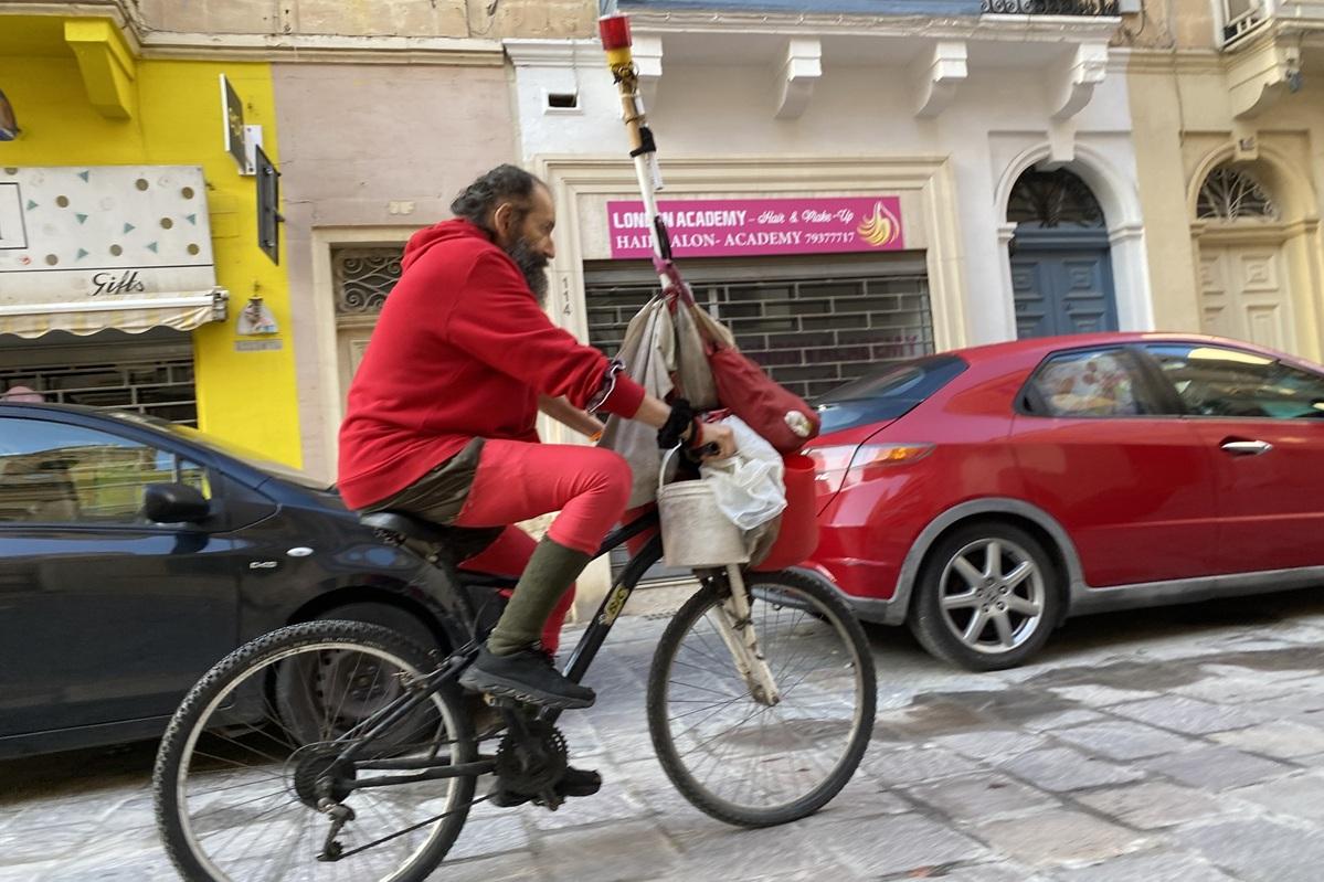 'Red Man' dressed in his trademark outfit was regularly seen cycling around the town on his way to feed cats or ducks or watering the promenade plants. Photo: Mark Camilleri/Facebook