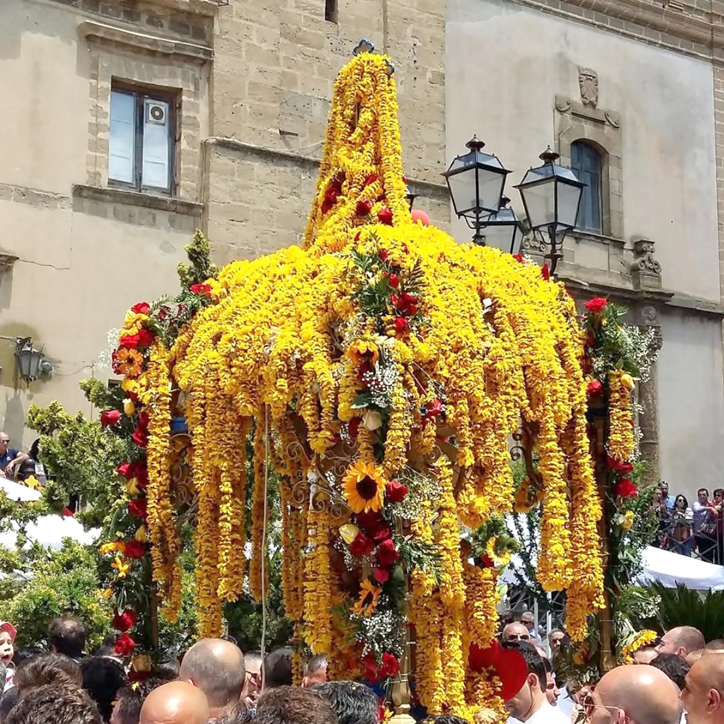 During the procession, people throw necklaces of yellow daisies over the cross.