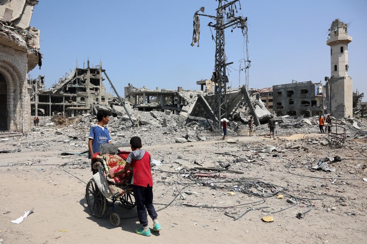 Palestinian boys use a wheelchair to transport quilts in the al-Tuffah neighbourhood of Gaza City. Photo: Omar Al-Qattaa/AFP