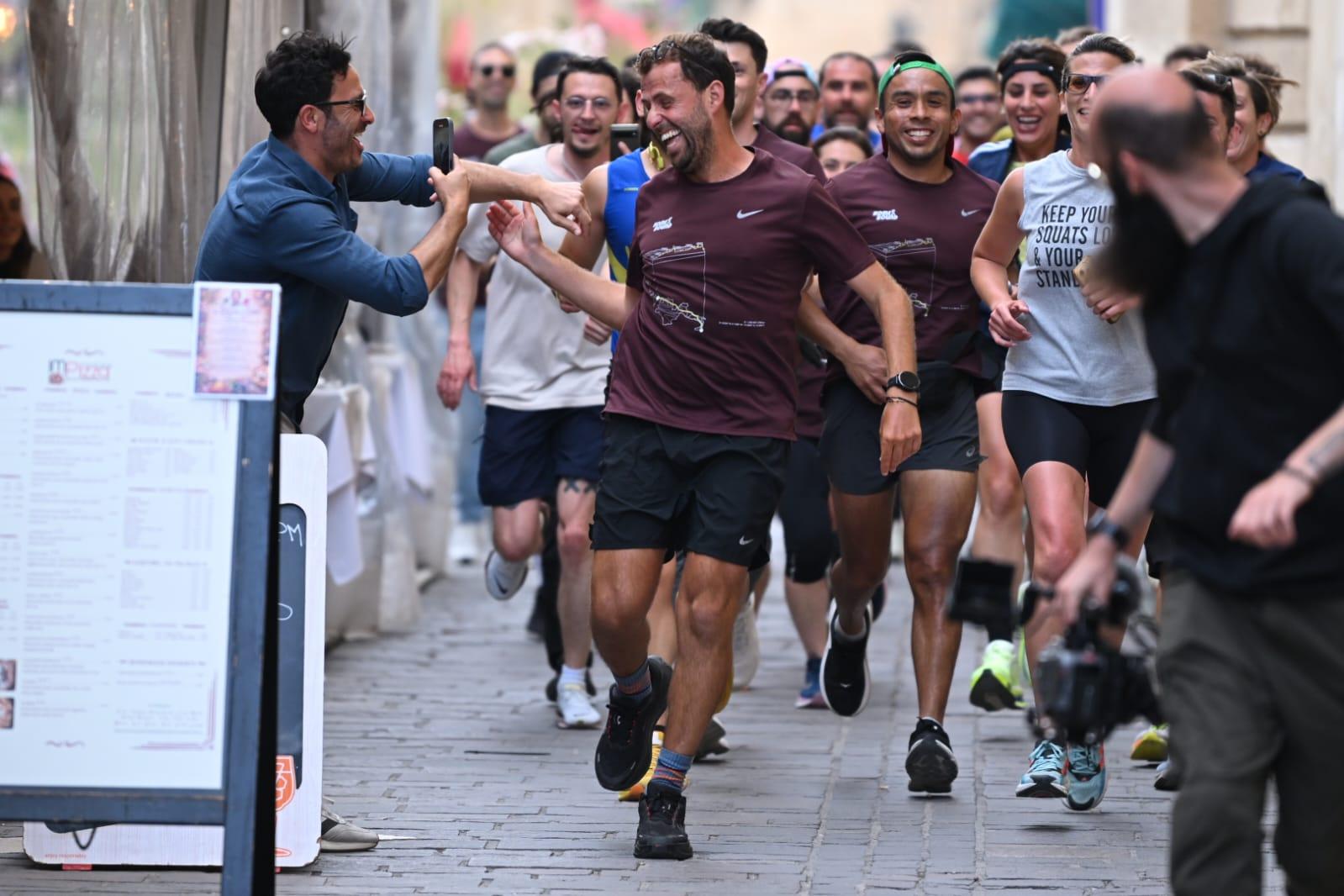 Zach Vella running the final leg home with supporters. Photo: Matthew Mirabelli