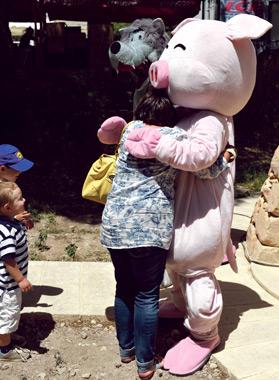 A visitor gets a hug from one of the Three Little Pigs &ndash; who appear to have made friends with the Big Bad Wolf in the background.