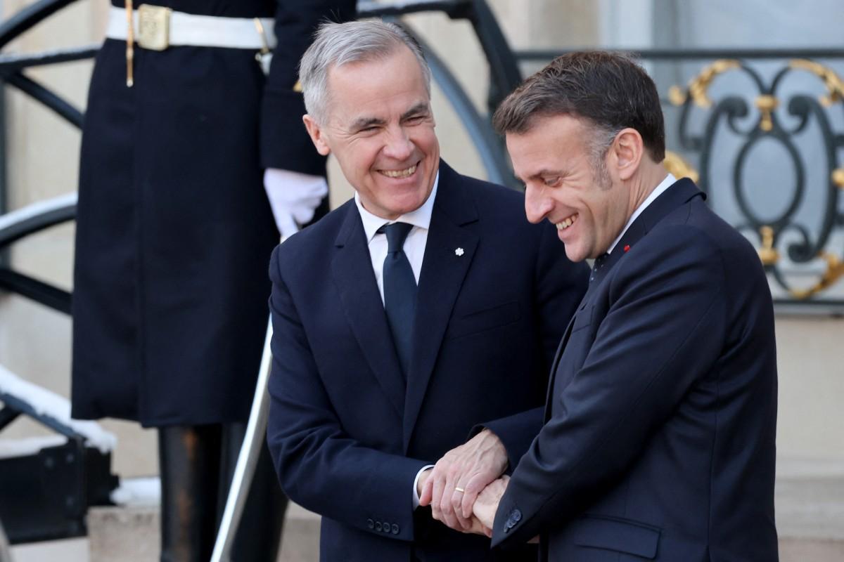 Mark Carney, left, greets Emmanuel Macron. Photo: AFP
