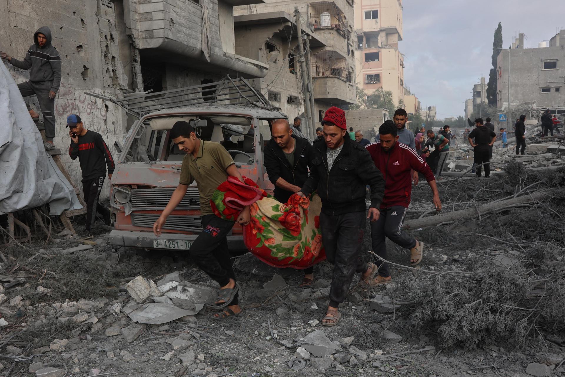 Palestinians carry the body of a victim after it was dug out from the rubble of a destroyed school. Photo: AFP