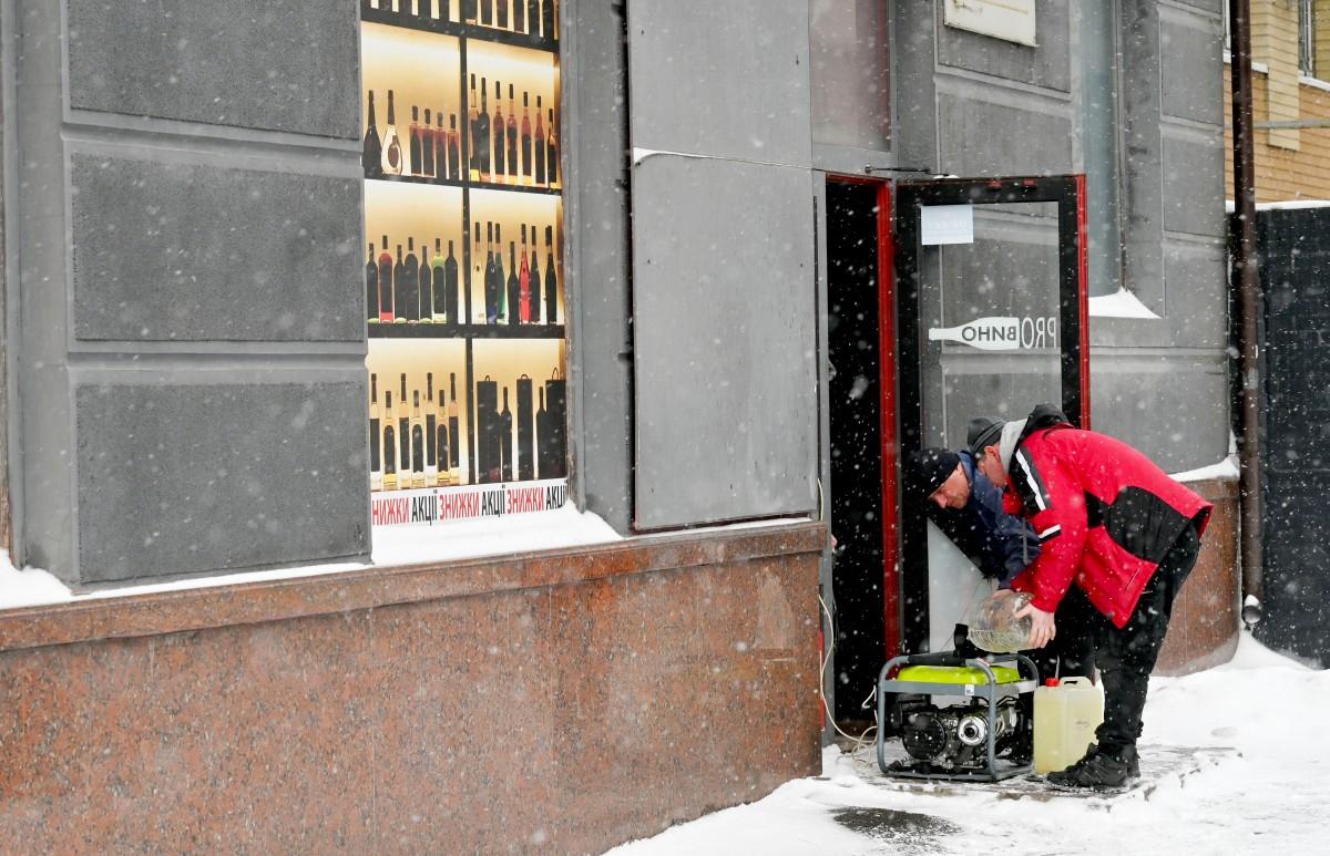 Employees refuel a power generator outside a shop during the blackout following Russian drones and missiles attacks in Kyiv. Photo: AFP