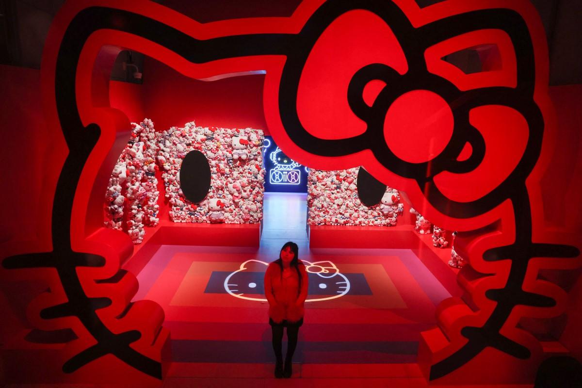 A gallery employee poses next to a Hello Kitty installation.