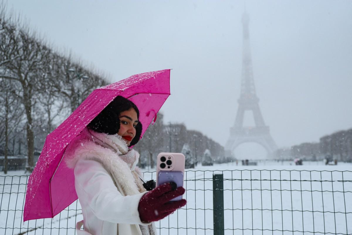 A woman takes a selfie on the snow-blanketed Champs-de-Mars near the Eiffel Tower in Paris.