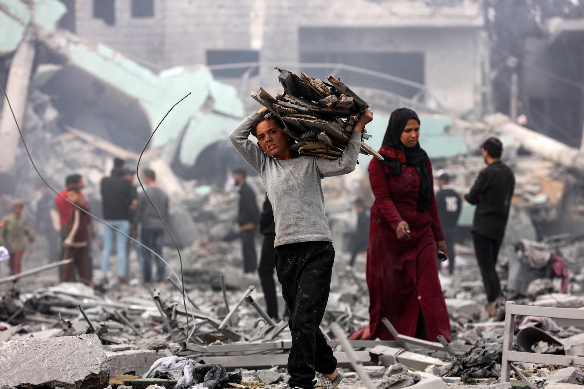 A young boy salvages some wood amid the devastation in the yard of a school. Photo: AFP