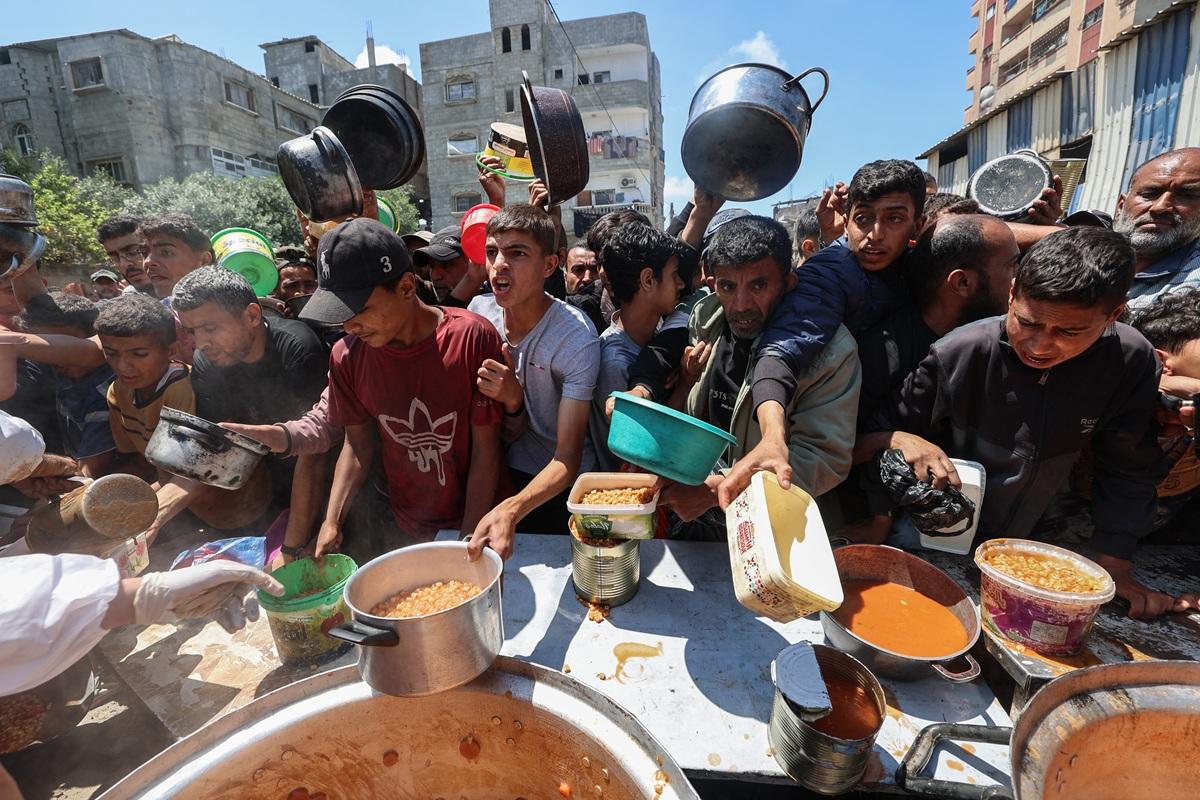 Palestinians queue for a portion of hot food distributed by a charity kitchen in the Nuseirat refugee camp in central Gaza. Israel said humanitarian aid will be distributed in Gaza "if necessary". Photo: AFP