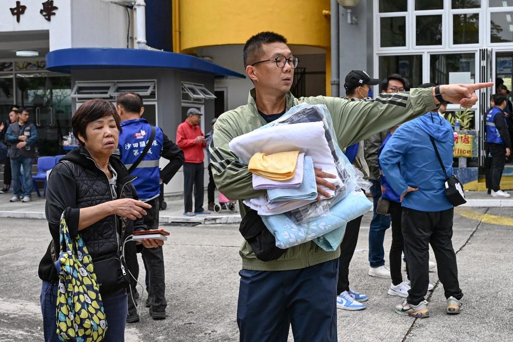 A resident collects blankets and towels at the Fung Leung Kit Secondary School, one of the community centres allocated for affected residents. Photo: AFP