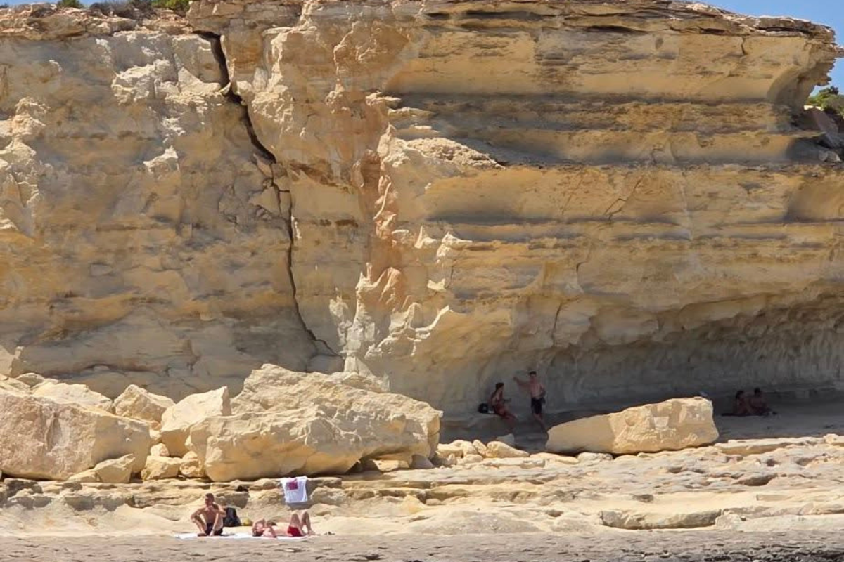 The photo uploaded to social media on Wednesday afternoon, showing swimmers standing underneath the seemingly dangerous boulder. Photo: Facebook / Charles Falzon