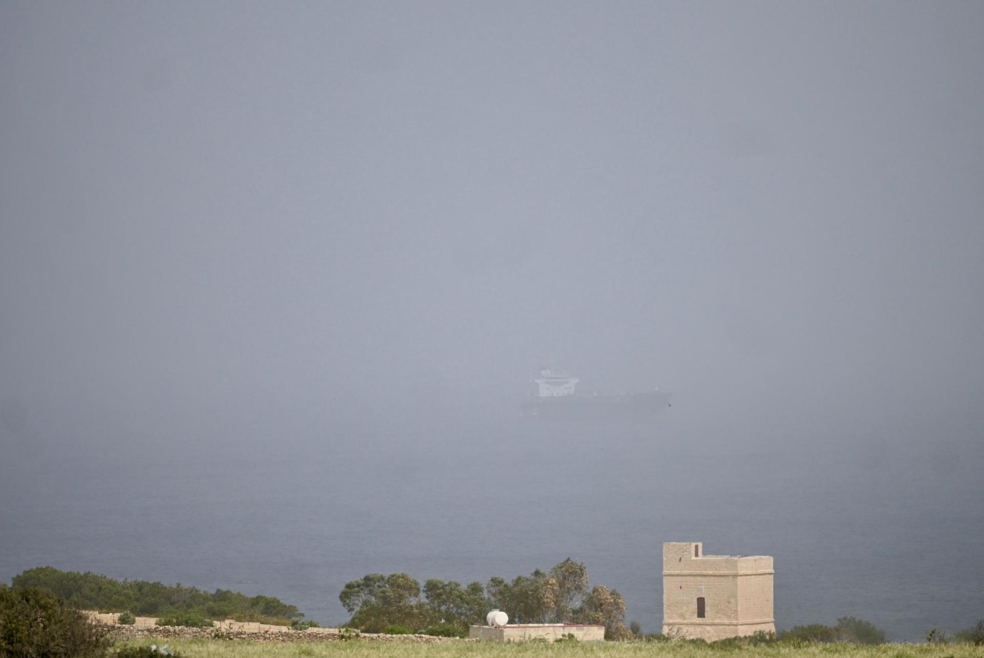 A tanker can be faintly seen out at sea through dust-filled skies. Photo: Jonathan Borg