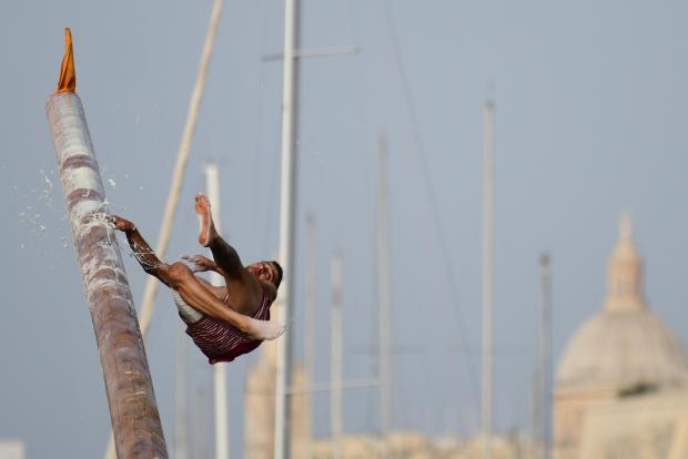A young man loses his balance during the Gostra contest held as part of the St Joseph feast in Msida on July 23. Participants run across a pole covered in grease, lard and cactus extract in an attempt to collect flags. Photo : Jonathan Borg