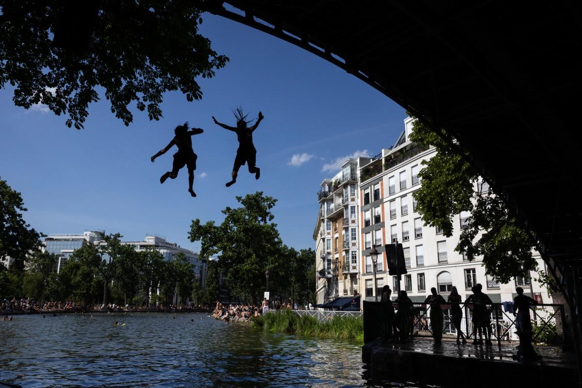 Young people jump from a bridge into the Canal Saint-Martin during a heatwave in Paris. Photo: AFP