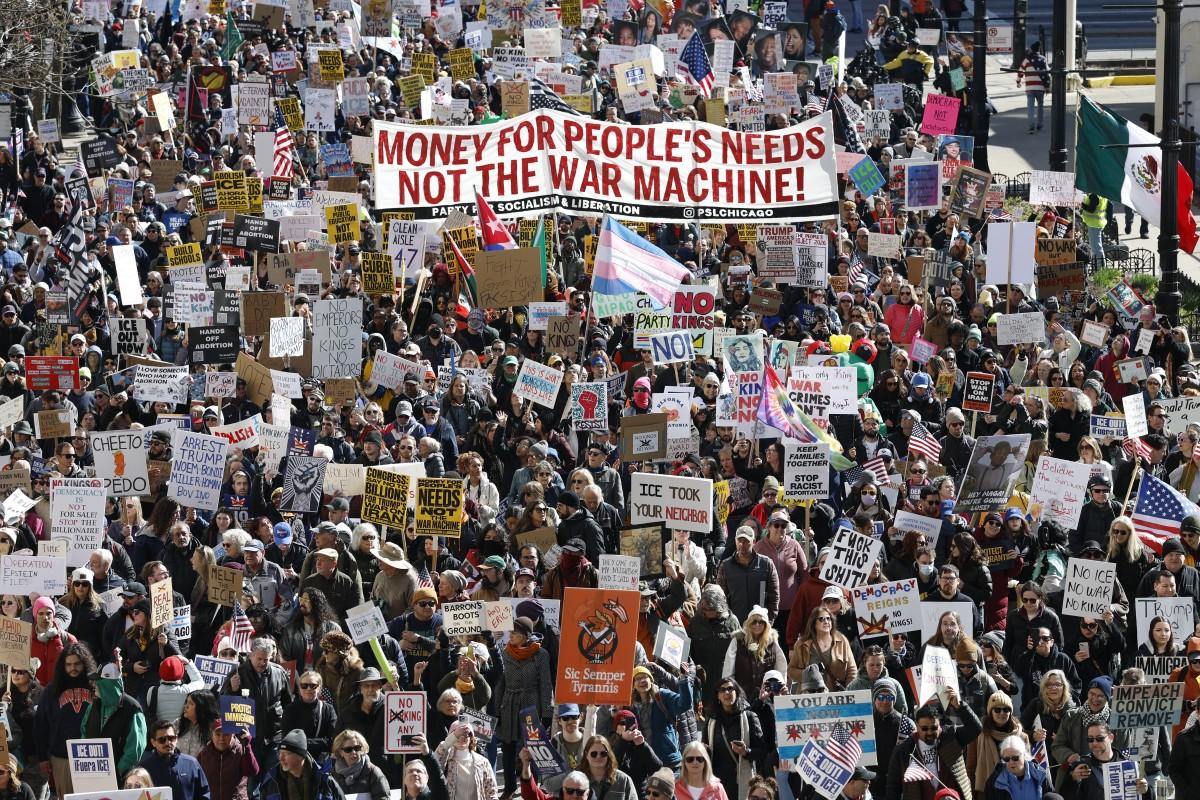 People hold signs and flags as they march during the protest in Chicago. Photo: AFP