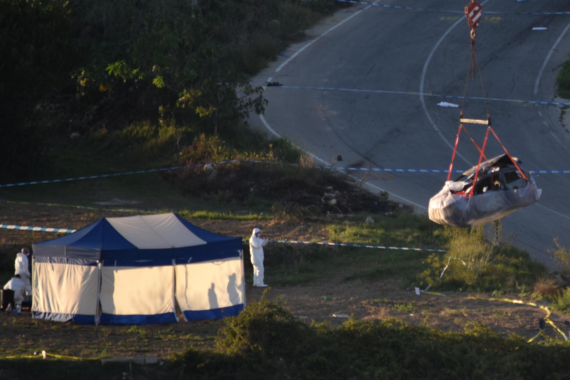 Forensic experts lift the blown up car at the scene of the assassination. Photo: Mark Zammit Cordina