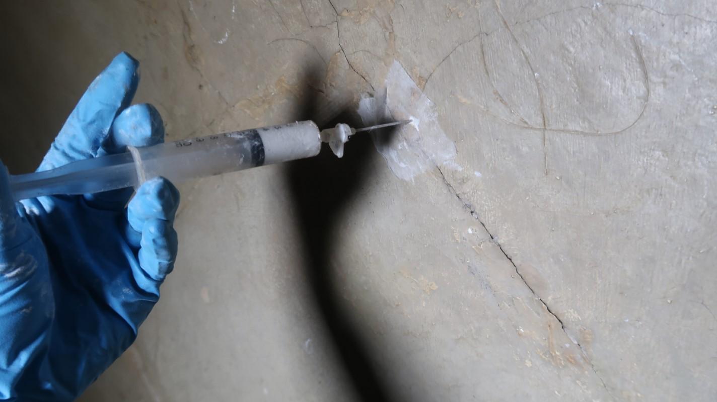 Compatible grouting material being injected into voids to re-establish adhesion and restore structural continuity.