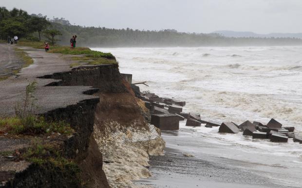 Locals stand next to a damaged road as Hurricane Irma moves off the northern coast of the Dominican Republic.