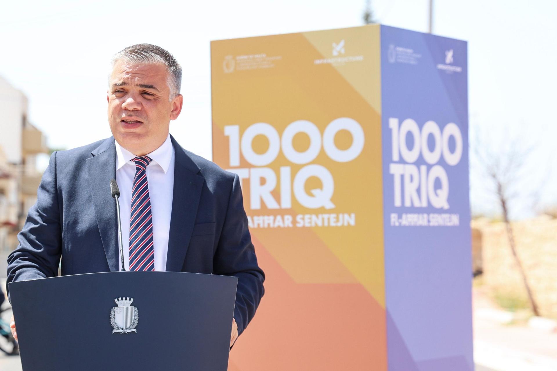 Bonett speaking against a backdrop that reads '1,000 roads in the past two years'. Photo: DOI
