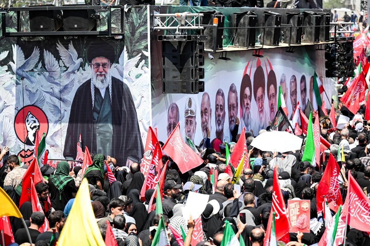 Mourners gather around one of the vehicles in the funeral procession for Iran's slain Supreme Leader Ali Khamenei displaying on its side a banner depicting slain or late figures including Khamenei. Photo: AFP