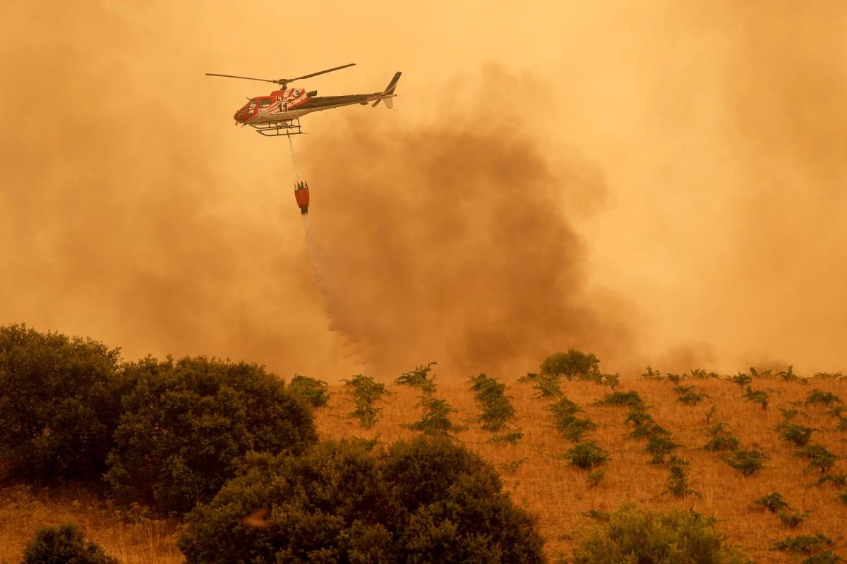 A firefighter helicopter dumps water on a wildfire in Cebreros. Photo: AFP