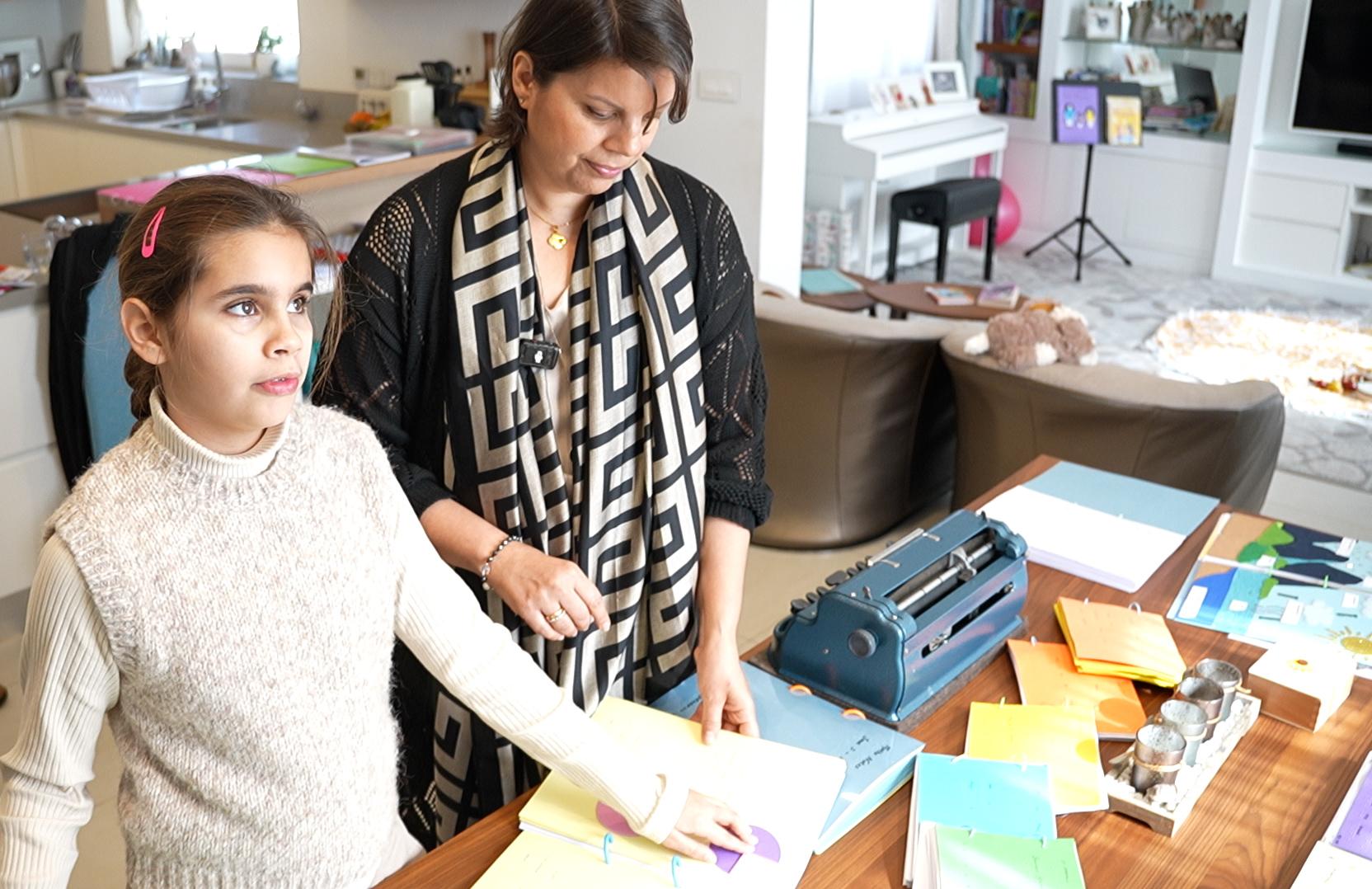 Melania using her hands to read an illustration with the help of her mother Marilena.