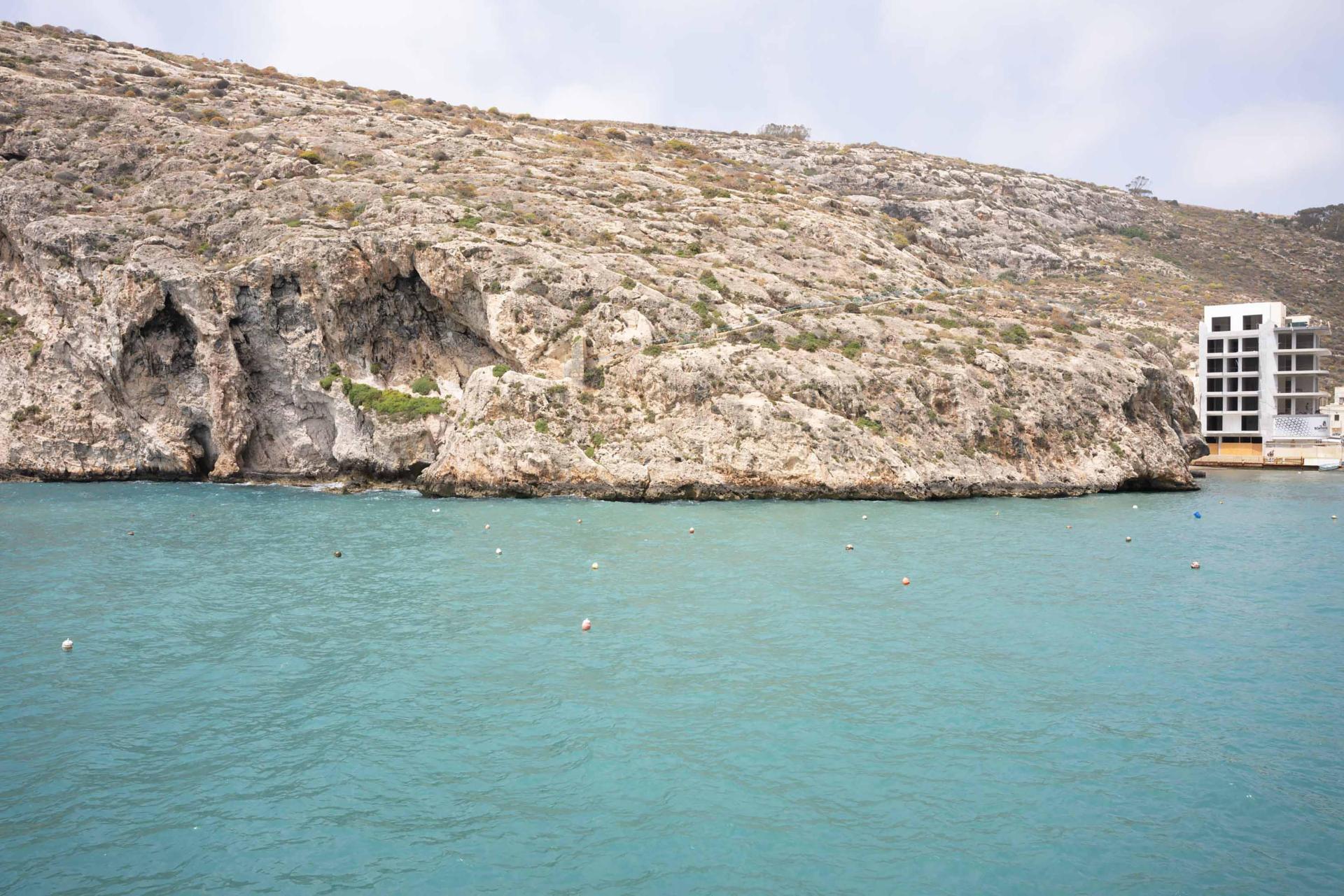 A construction site intrudes on this photograph of Xlendi Bay.