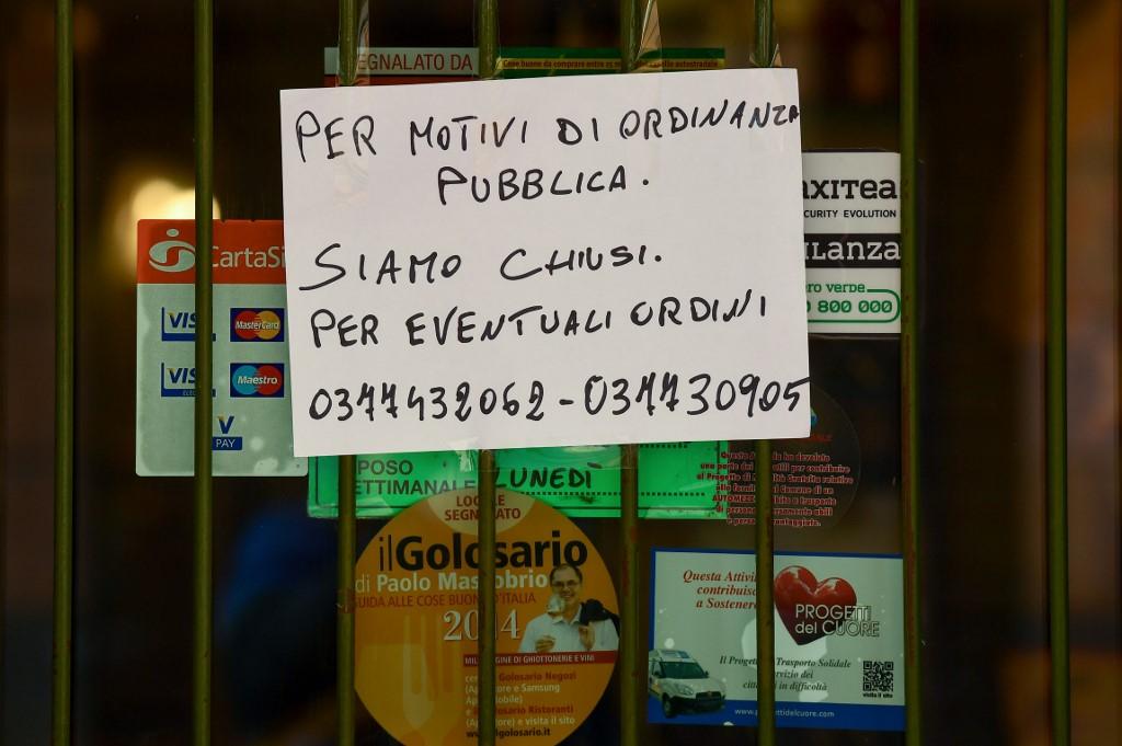 sign reading "Closed by Municipal Decree, for any orders call the following numbers " is put up on a shop's window in Codogno, southeast of Milan. Photo: AFP