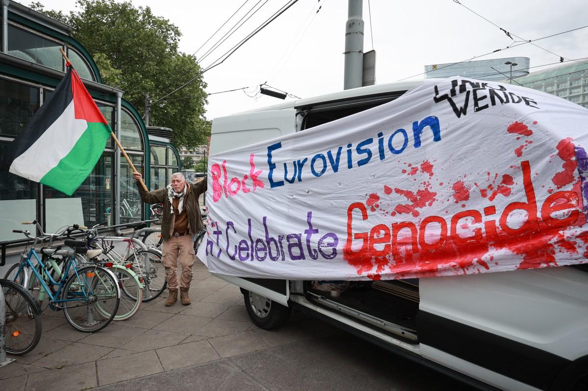 An activist stands next to a banner reading "Block Eurovision" to protest against the participation of Israel ahead the first semifinal of the Eurovision Song Contest, Vienna, Austria. Photo: AFP
