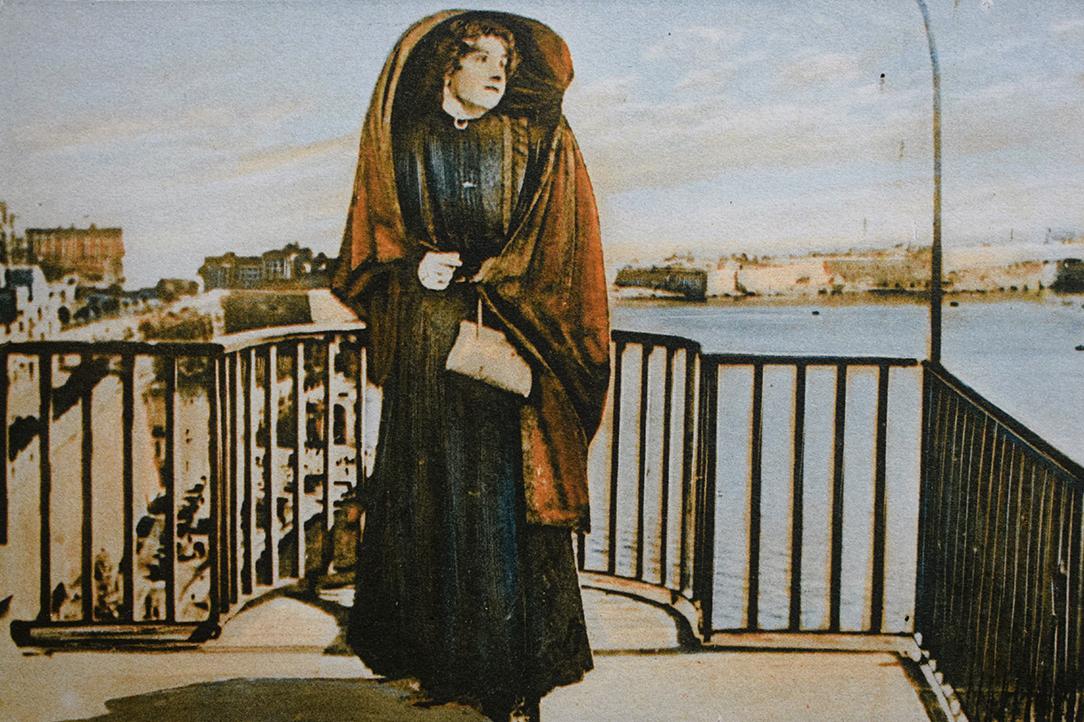 Colourised postcard of a woman in 'għonnella'.
