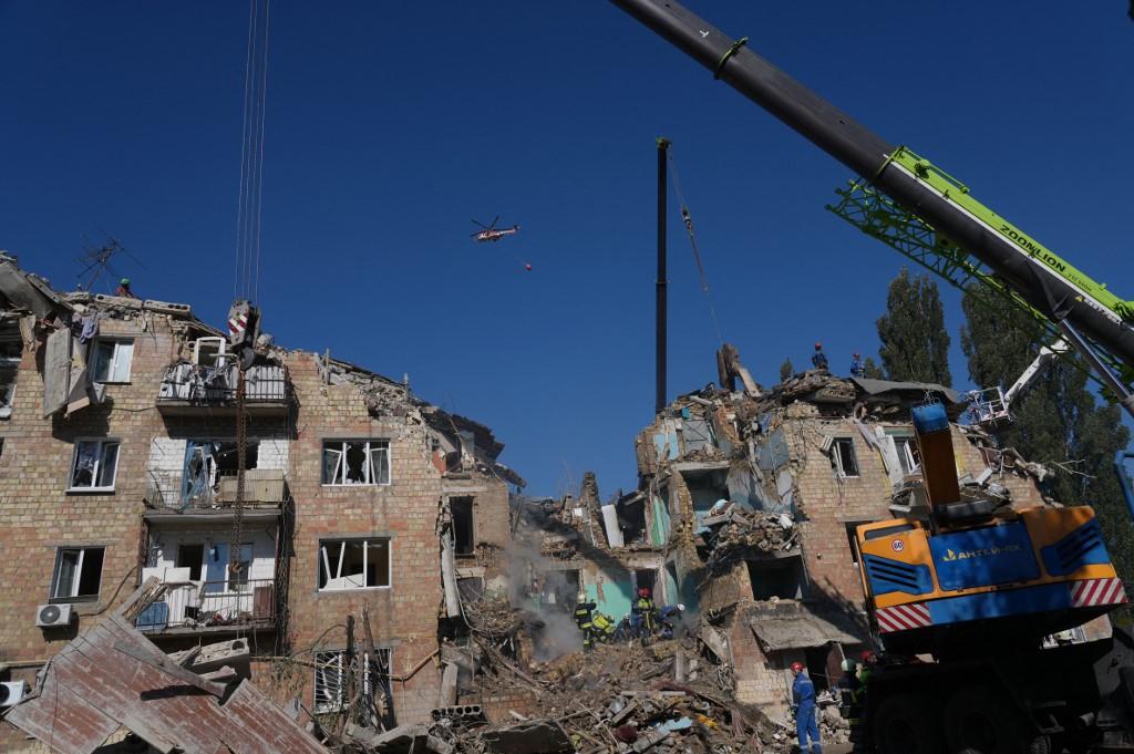 A firefighting helicopter flies over a heavily damaged residential building. Photo: AFP