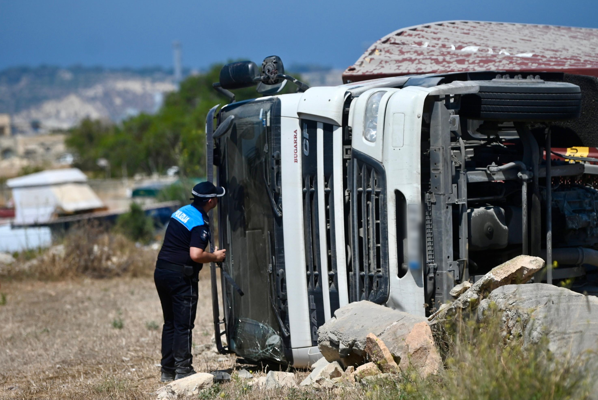 A police officer peers inside the cabin of one of the vehicles which overturned following the collision on Triq Ħal Far. Photo: Jonathan Borg
