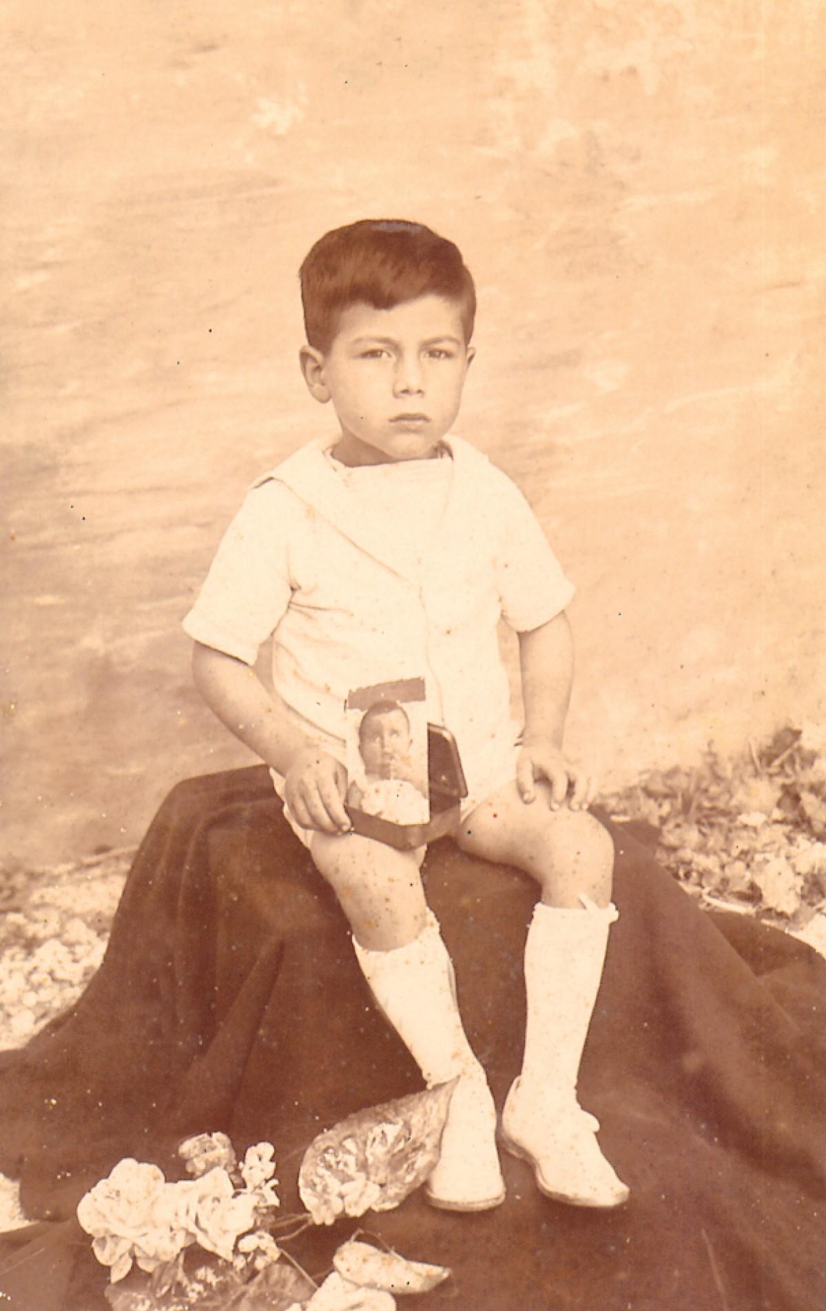 Nikol as a young boy in Għarb, holding a photo of his younger brother Giovanni, who died in his infancy.