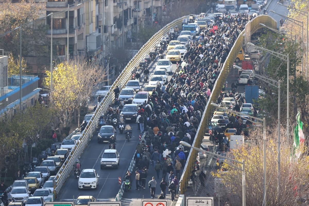 Demonstrating shopkeepers walk across a bridge in Tehran. Photo: AFP