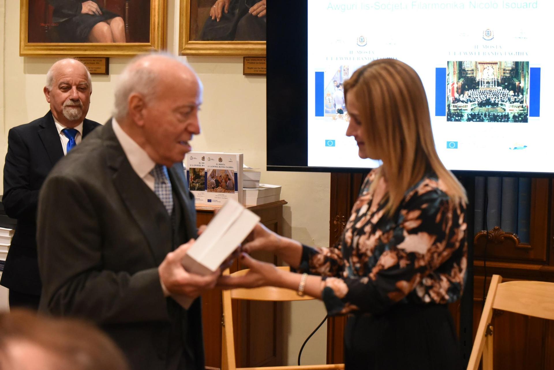 The author Saviour Dimech presents the first copy to the President of the Society, Sylvia Micallef, during the launching on November 29, 2025.