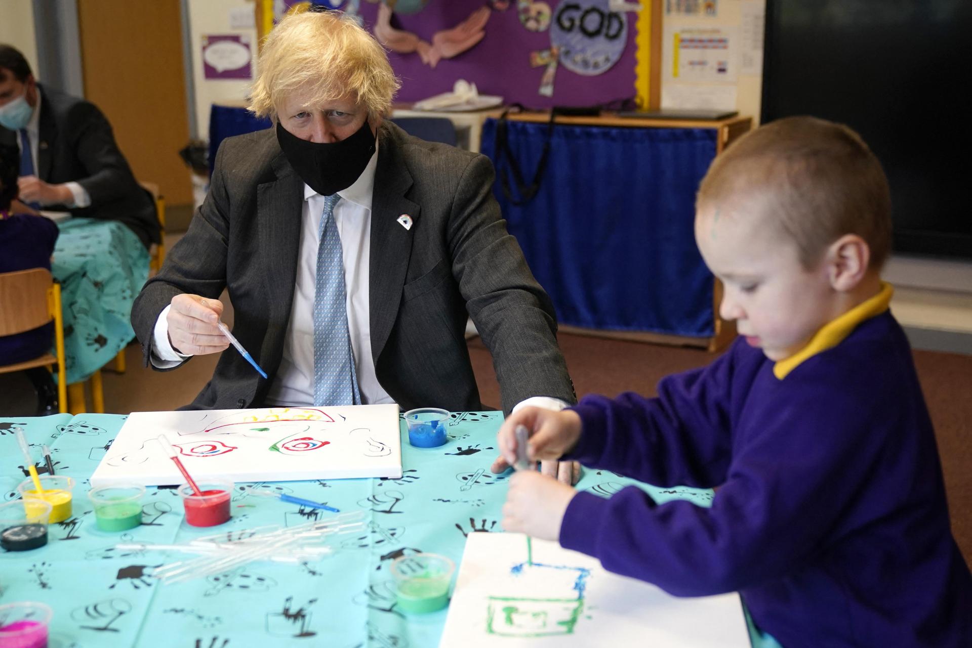 Britain&rsquo;s Prime Minister Boris Johnson, wearing a face covering, paints a picture of a face as he joins a reception class in their painting lesson, during a visit to St Mary's C.E. Primary School in Stoke-on-Trent, central England on March 1, 2021, to see how their preparations are going ahead of students returning on March 8, after England&rsquo;s third lockdown. Photo: AFP
