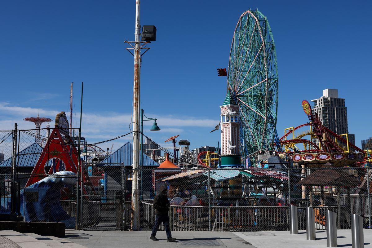 A pedestrian walks past the Coney Island amusement park.