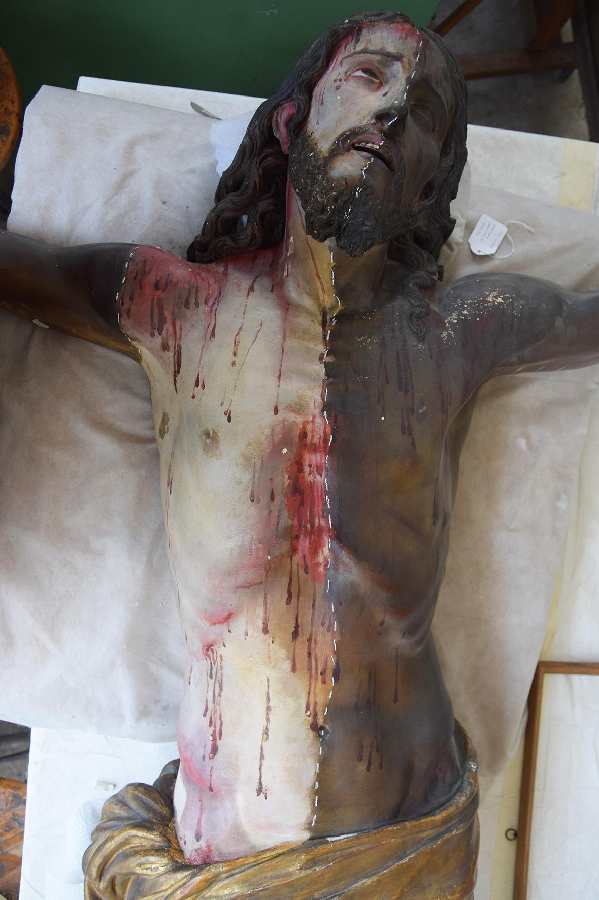 Detail of the crucifix during cleaning, showing the contrast between treated and untreated areas.