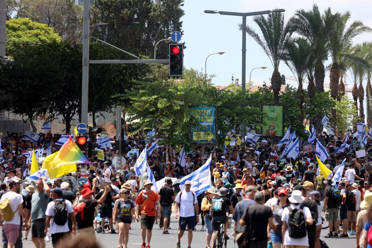 Demonstrators raise flags during an anti-government protest. Photo: GIL COHEN-MAGEN / AFP.
