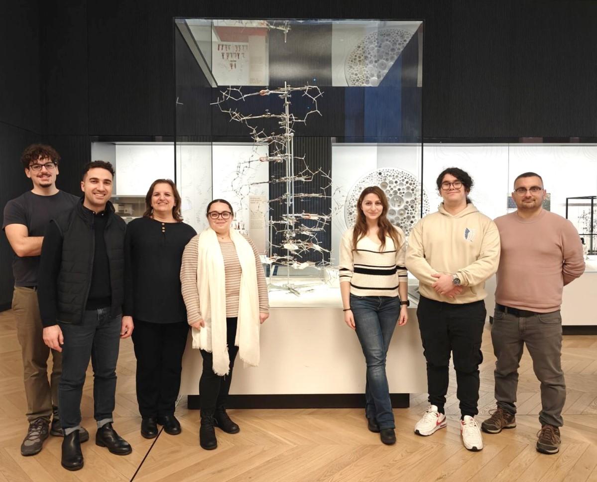 Researchers from the TargetMI project at the University of Malta, funded by the EU's EIC Pathfinder grant, standing by a DNA model at the Science Museum in London during the Festival of Genomics and Biodata 2025.