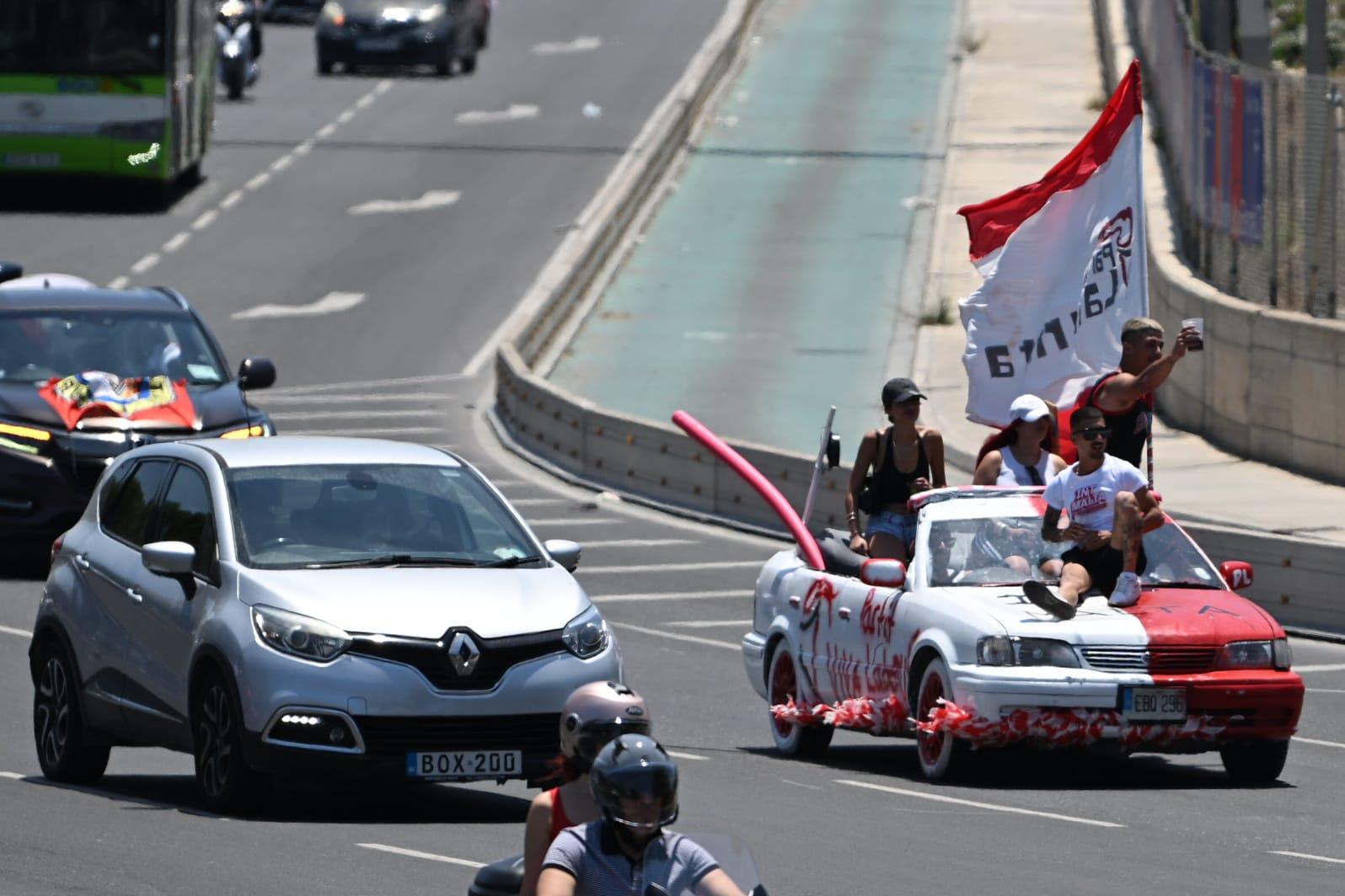 A Labour supporter sits on the bonnet of a moving car on Marsa's busy Aldo Moro road. Photo: Matthew Mirabelli