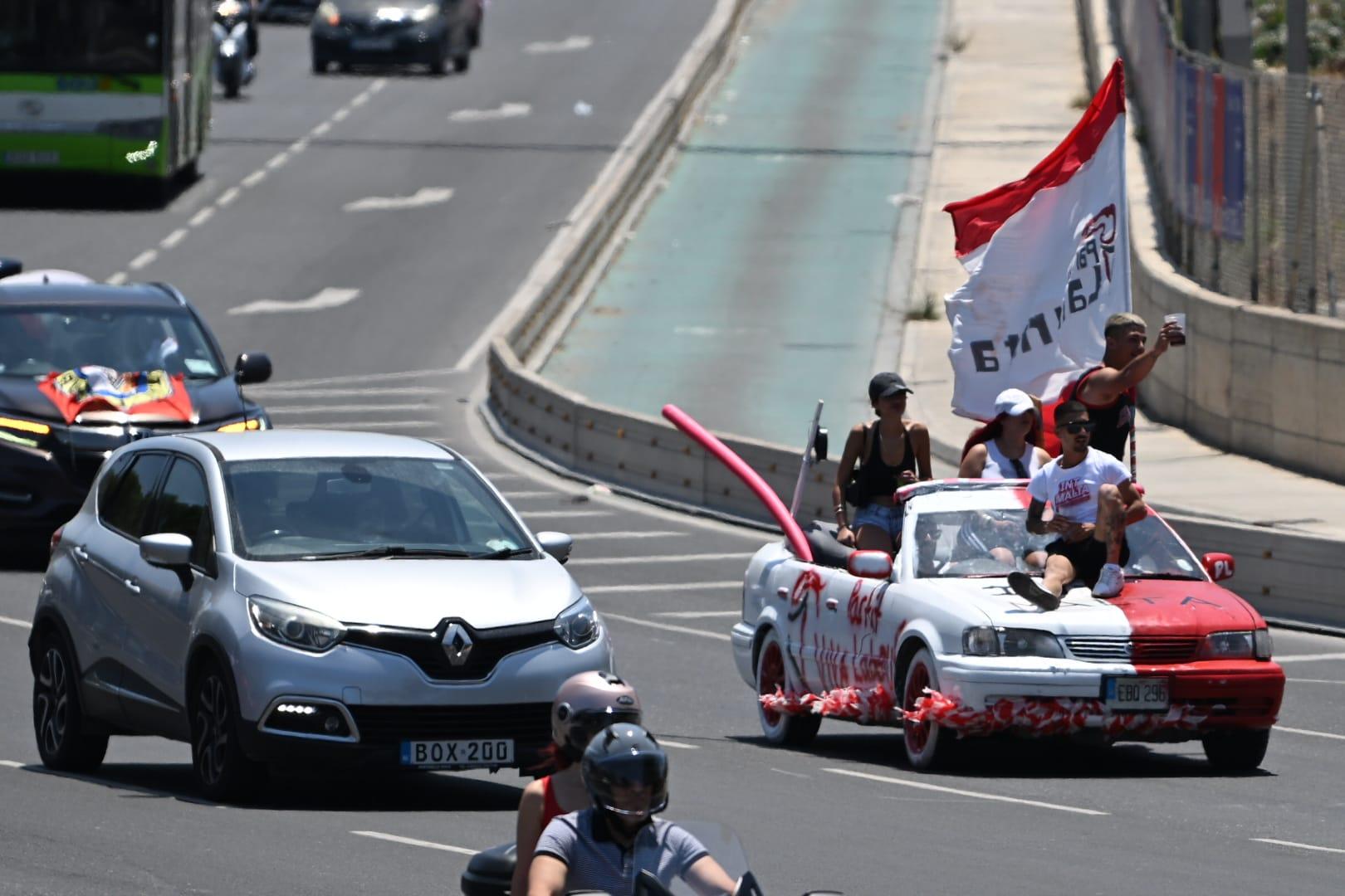 A Labour supporter sits on the bonnet of a moving car on Marsa's busy Aldo Moro road. Photo: Matthew Mirabelli