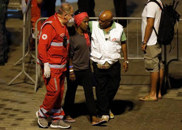 An unaccompanied minor migrant is helped after disembarking from the Italian coast guard vessel Diciotti.